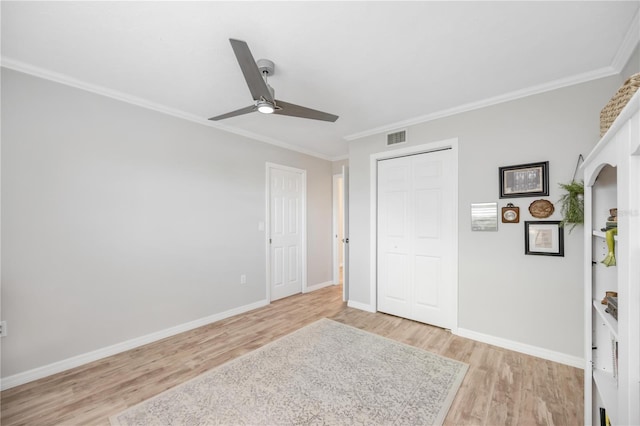 unfurnished bedroom with ornamental molding, a closet, ceiling fan, and light hardwood / wood-style flooring