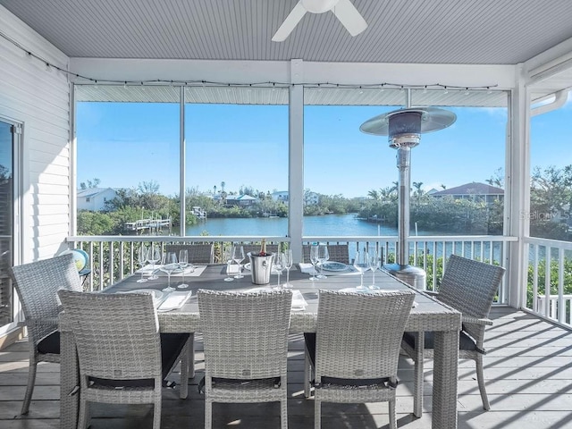 sunroom with ceiling fan and a water view