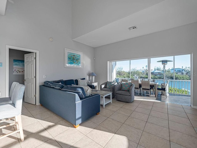 tiled living room with a towering ceiling and a water view