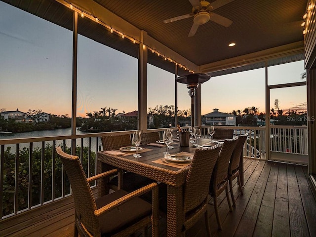 deck at dusk featuring ceiling fan and a water view