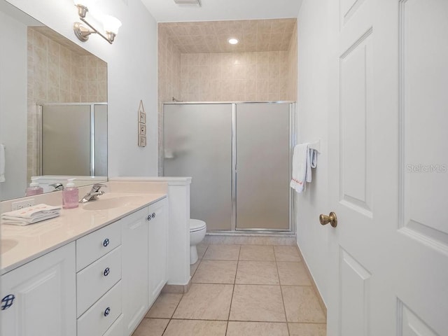 bathroom with a shower with door, vanity, tile patterned flooring, and toilet