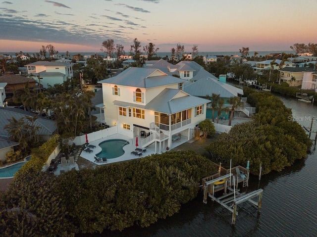 aerial view at dusk featuring a water view