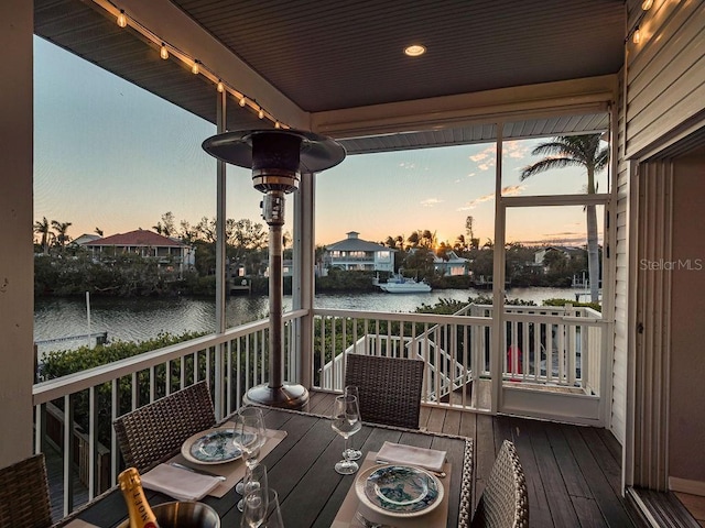 deck at dusk featuring a water view