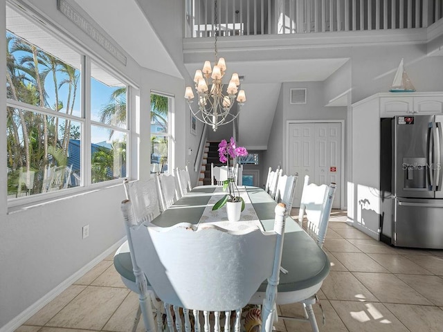 tiled dining space featuring a towering ceiling and a chandelier