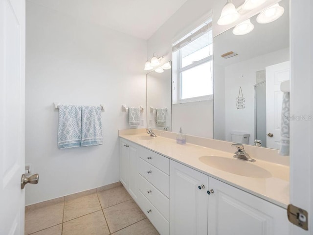 bathroom featuring tile patterned flooring, vanity, a shower with shower door, and toilet