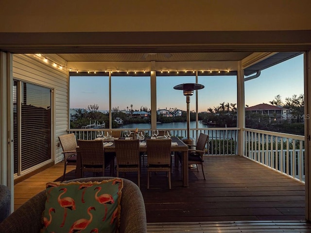 deck at dusk featuring a water view