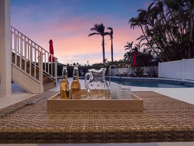 pool at dusk featuring a patio