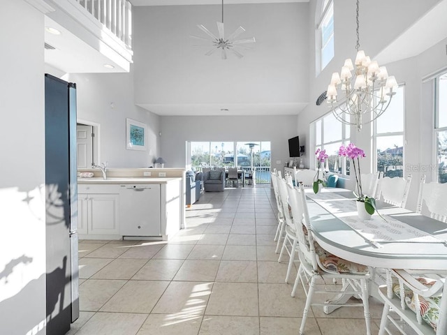 dining room featuring a towering ceiling, sink, light tile patterned floors, and a notable chandelier