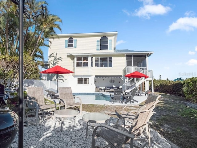 back of property with a fenced in pool, a patio, and a sunroom