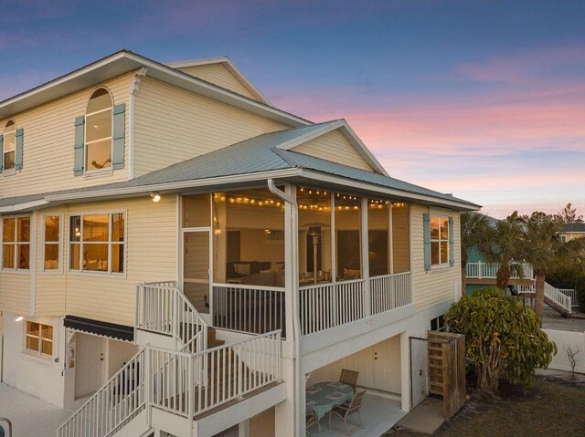 114 Gull Dr, Anna Maria, FL 34216 - back of house at dusk featuring stairway, a sunroom, a patio, and metal roof