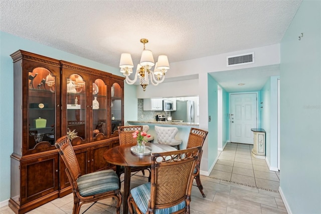 tiled dining space with an inviting chandelier and a textured ceiling