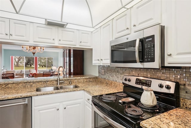 kitchen with sink, white cabinetry, stainless steel appliances, light stone countertops, and decorative backsplash