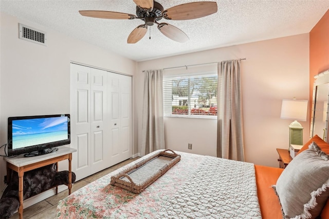 tiled bedroom featuring a textured ceiling, ceiling fan, and a closet