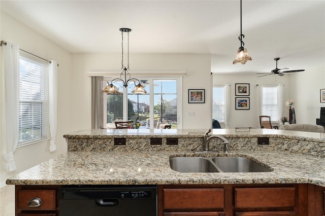 kitchen featuring pendant lighting, dishwasher, sink, and light stone counters