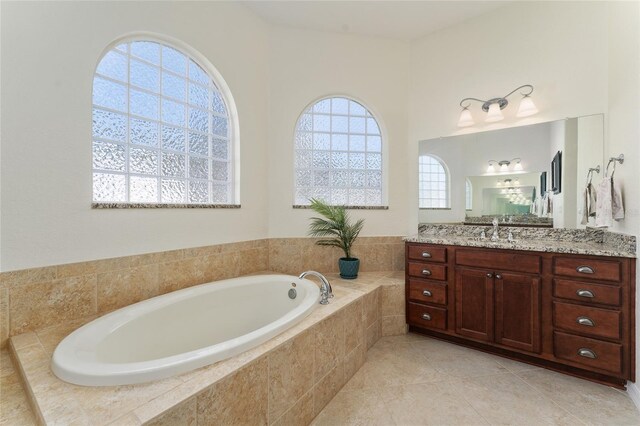 bathroom featuring vanity, tile patterned flooring, and tiled bath