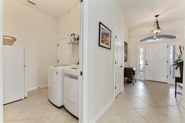 clothes washing area with a high ceiling, separate washer and dryer, and light tile patterned floors