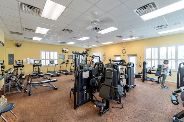 workout area featuring a paneled ceiling, electric panel, and ceiling fan