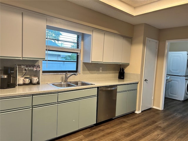 kitchen featuring white cabinetry, sink, dark hardwood / wood-style flooring, stacked washer and clothes dryer, and stainless steel dishwasher