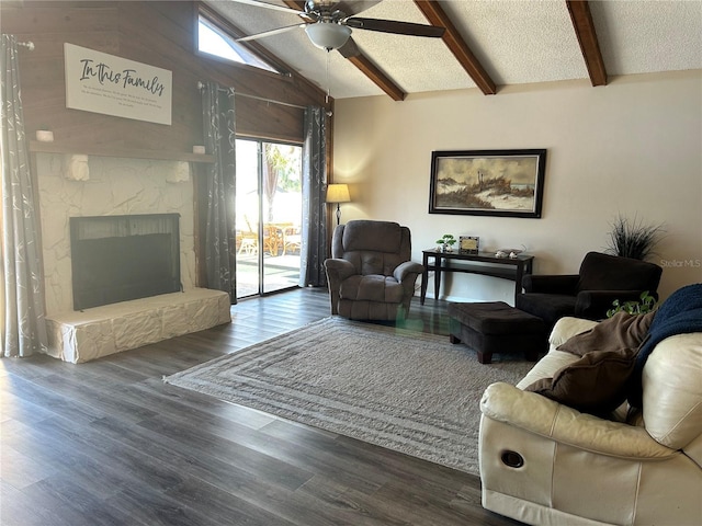 living room featuring a stone fireplace, lofted ceiling with beams, a textured ceiling, dark hardwood / wood-style floors, and ceiling fan