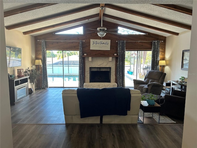 living room with vaulted ceiling with beams, dark hardwood / wood-style floors, a fireplace, a healthy amount of sunlight, and a textured ceiling