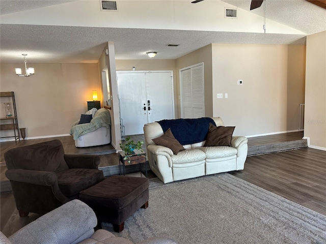 living room featuring ceiling fan with notable chandelier, wood-type flooring, vaulted ceiling, and a textured ceiling