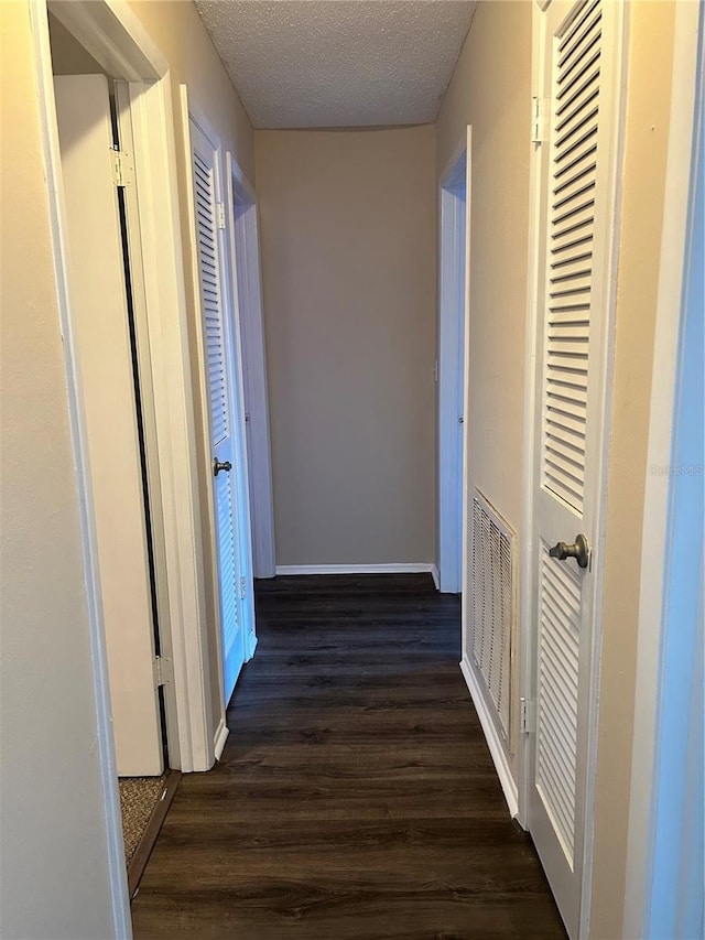 hallway featuring dark hardwood / wood-style floors and a textured ceiling