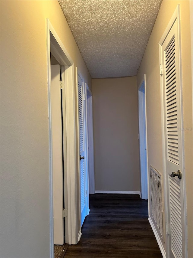 hallway featuring dark hardwood / wood-style flooring and a textured ceiling