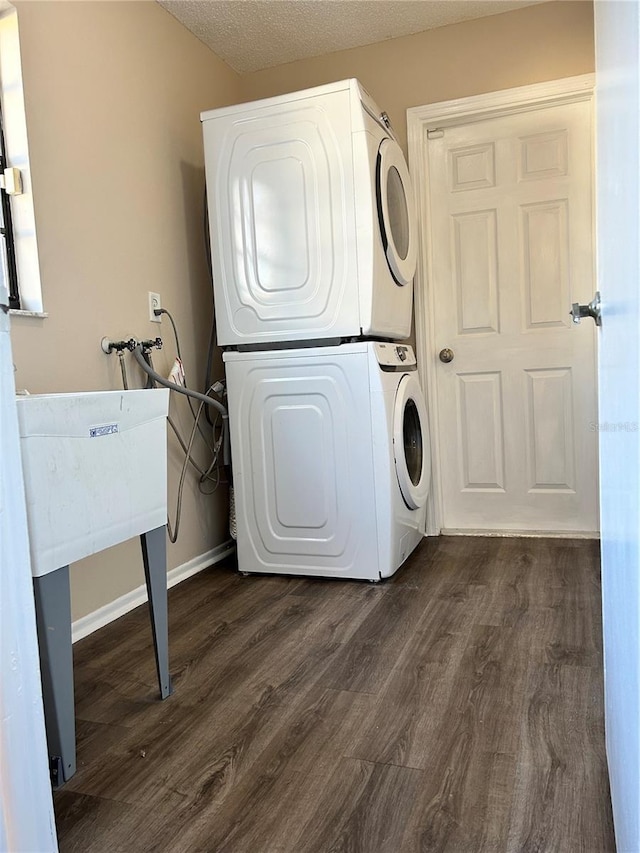 washroom with dark hardwood / wood-style floors, a textured ceiling, and stacked washer / dryer