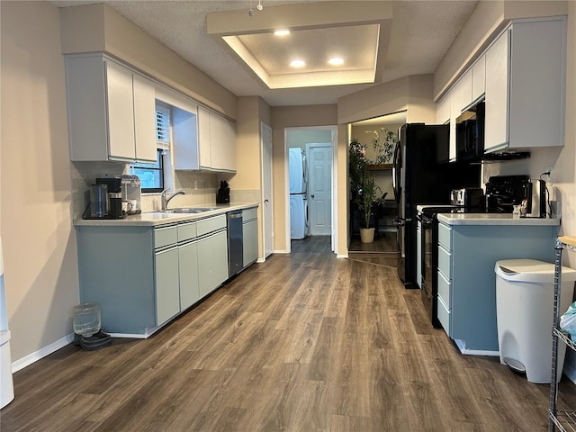 kitchen with sink, dark hardwood / wood-style floors, black appliances, white cabinets, and a raised ceiling