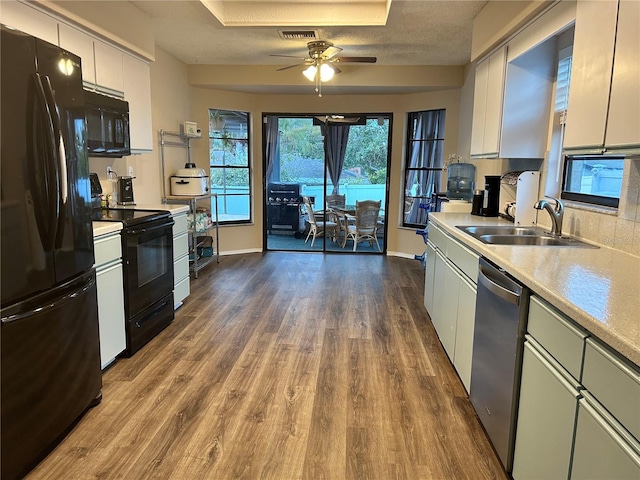 kitchen with sink, white cabinetry, a textured ceiling, hardwood / wood-style flooring, and black appliances