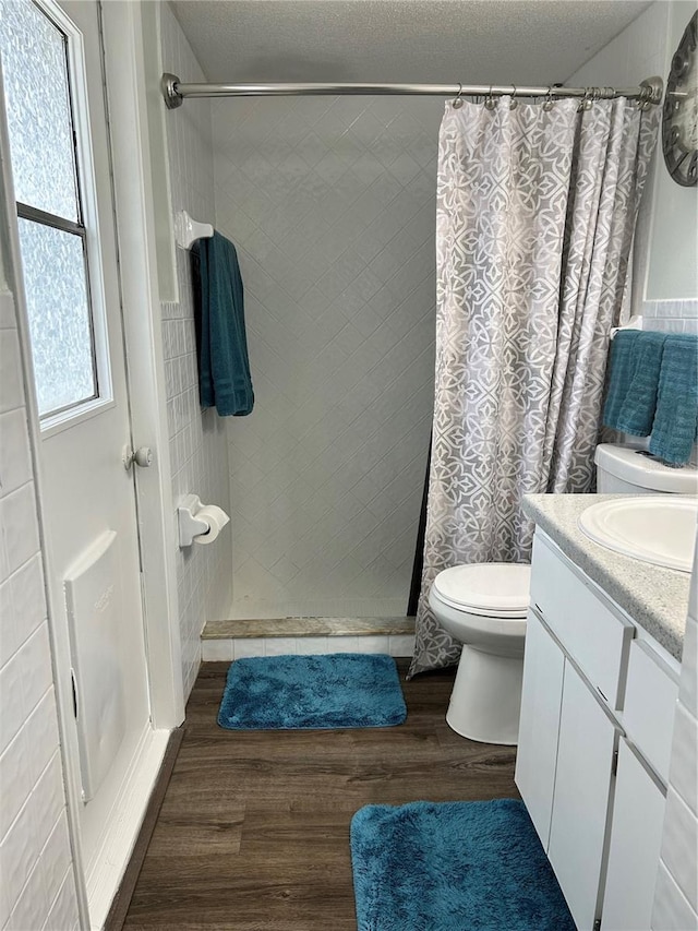 bathroom with hardwood / wood-style flooring, a healthy amount of sunlight, vanity, and walk in shower