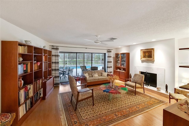 living room with ceiling fan, wood-type flooring, and a textured ceiling