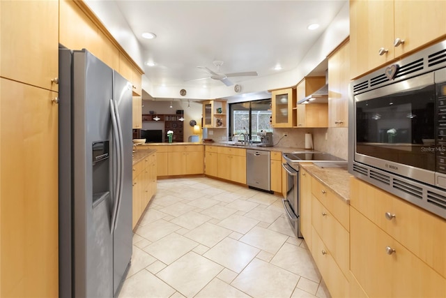 kitchen with sink, light brown cabinets, appliances with stainless steel finishes, ceiling fan, and wall chimney range hood