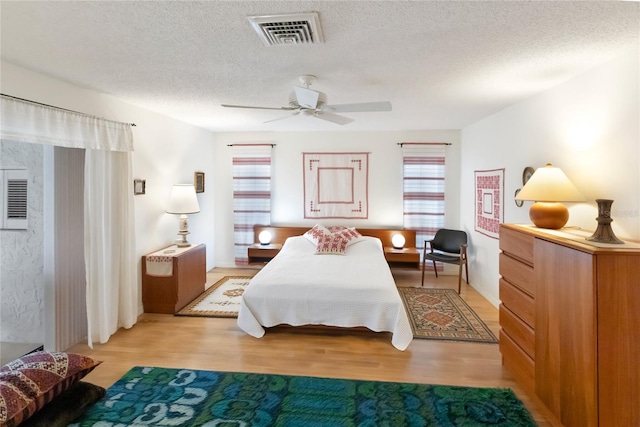 bedroom with ceiling fan, a textured ceiling, and light wood-type flooring