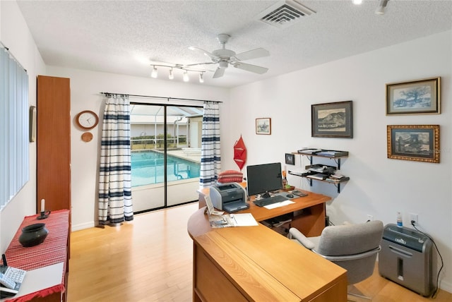 home office with ceiling fan, light hardwood / wood-style flooring, and a textured ceiling