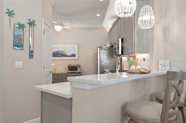 kitchen with gray cabinets, a breakfast bar area, ornamental molding, kitchen peninsula, and stainless steel appliances