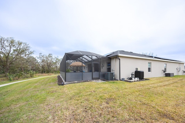 view of home's exterior with central AC unit, glass enclosure, and a lawn