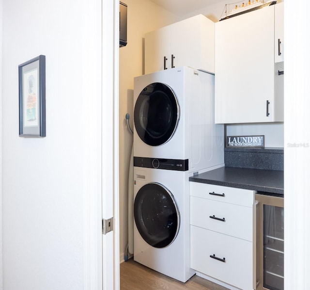 laundry area featuring stacked washer and dryer, beverage cooler, and light hardwood / wood-style flooring