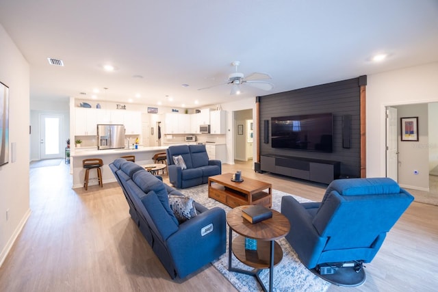 living room featuring ceiling fan and light hardwood / wood-style floors