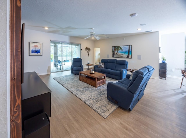 living room with ceiling fan, wood-type flooring, and a textured ceiling