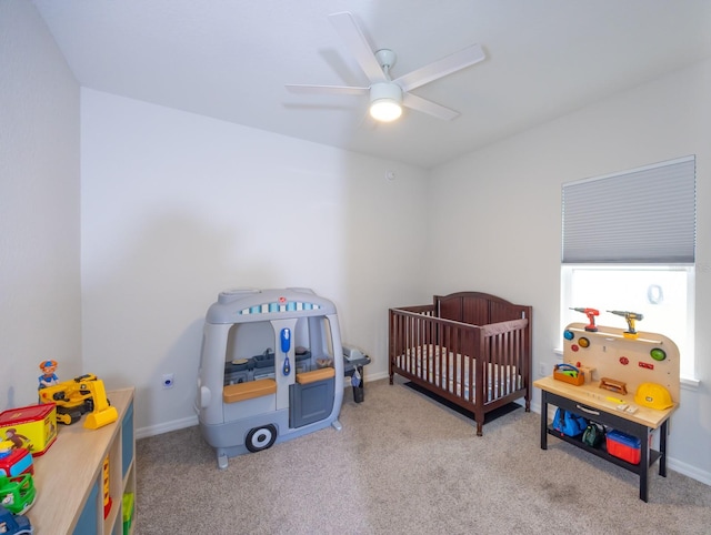 carpeted bedroom with ceiling fan and a crib