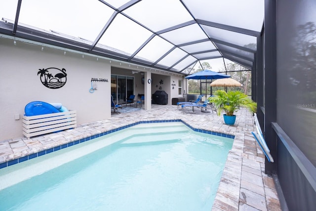 view of swimming pool with a grill, a patio, and glass enclosure