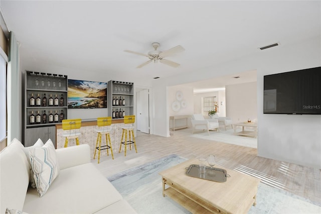 living room with ceiling fan and bar area