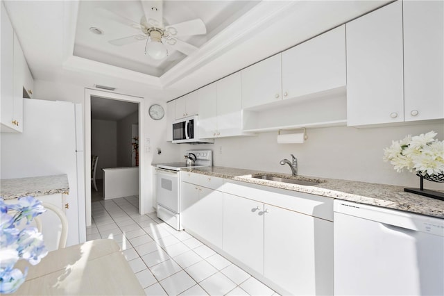 kitchen featuring white cabinetry, sink, light tile patterned floors, a tray ceiling, and white appliances