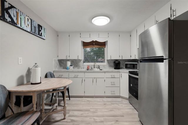 kitchen with sink, stainless steel appliances, light hardwood / wood-style floors, white cabinets, and decorative backsplash