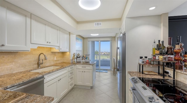 kitchen with light stone counters, appliances with stainless steel finishes, sink, and white cabinets