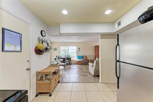 kitchen with light tile patterned floors and stainless steel refrigerator