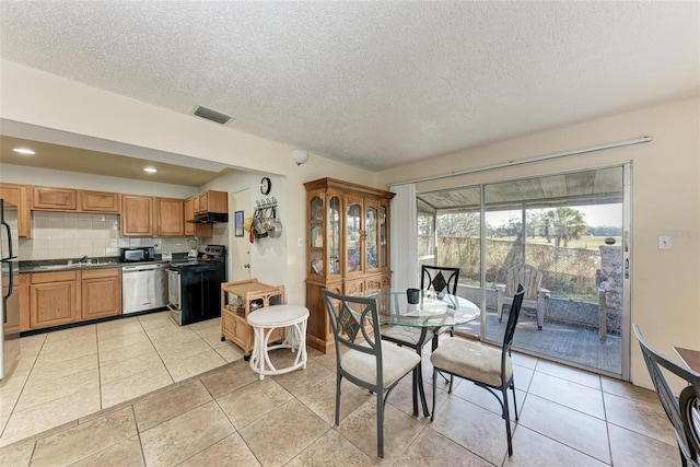 dining space featuring sink, a textured ceiling, and light tile patterned floors