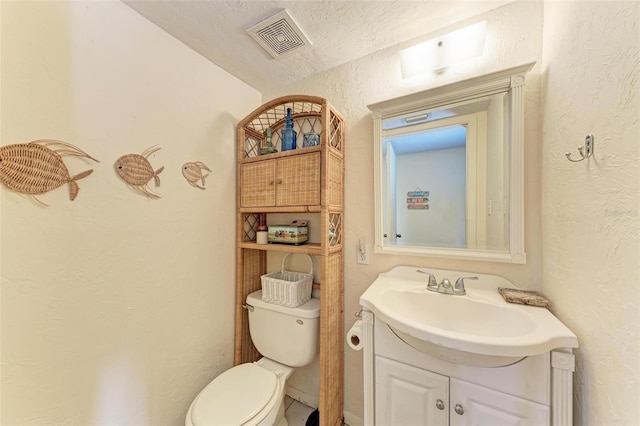 bathroom featuring vanity, toilet, and a textured ceiling