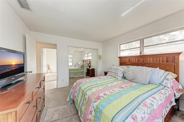 bedroom with light colored carpet, a closet, and a textured ceiling